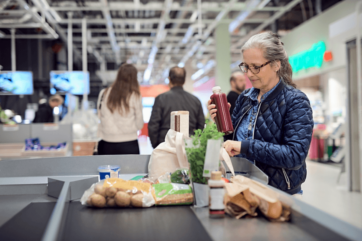 Donna al supermercato con prodotti alimentari. Webinar FSSC 24000 per responsabilità etico-sociale.