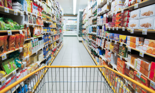 Corsia di supermercato con scaffali pieni di prodotti e carrello. Spesa alimentare. - inflazione