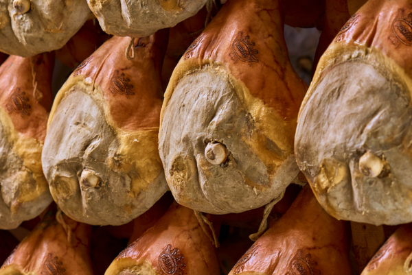 Stagionatura Prosciutto di Parma DOP. Salumi appesi, tradizione culinaria italiana.