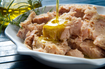 Tonno all'olio d'oliva in piatto bianco. Ricetta con tonno, olio, e rosmarino. - conserve ittiche