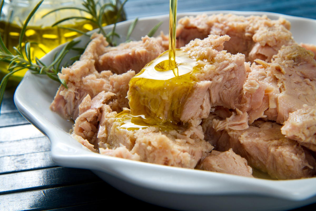 Tonno all'olio d'oliva in piatto bianco. Ricetta con tonno, olio, e rosmarino. - conserve ittiche