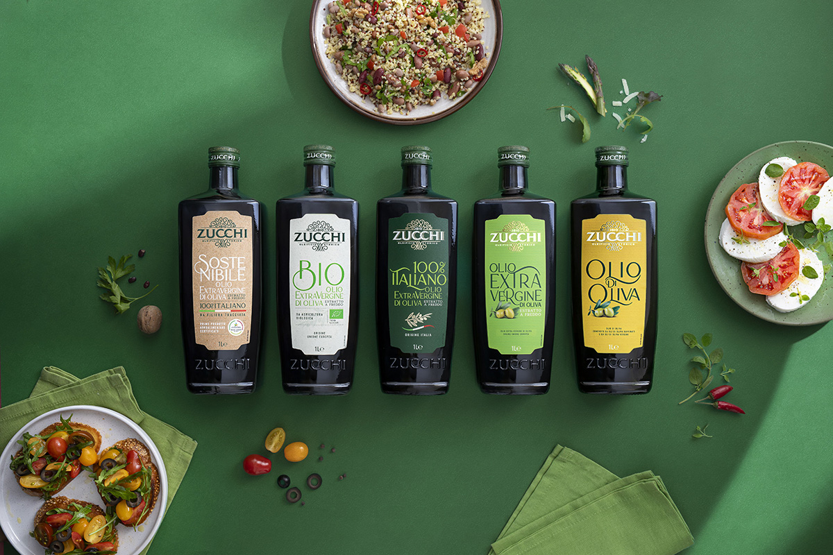 Olio Zucchi: gamma di oli extra vergine d'oliva (EVO) 100% italiani, bio e sostenibili. Bottiglie nere su sfondo verde.