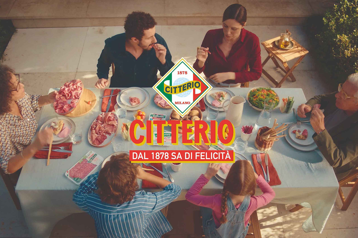 Famiglia a tavola con salumi Citterio. Tavolata con affettati, snack e logo Citterio. Prodotti Citterio dal 1878.