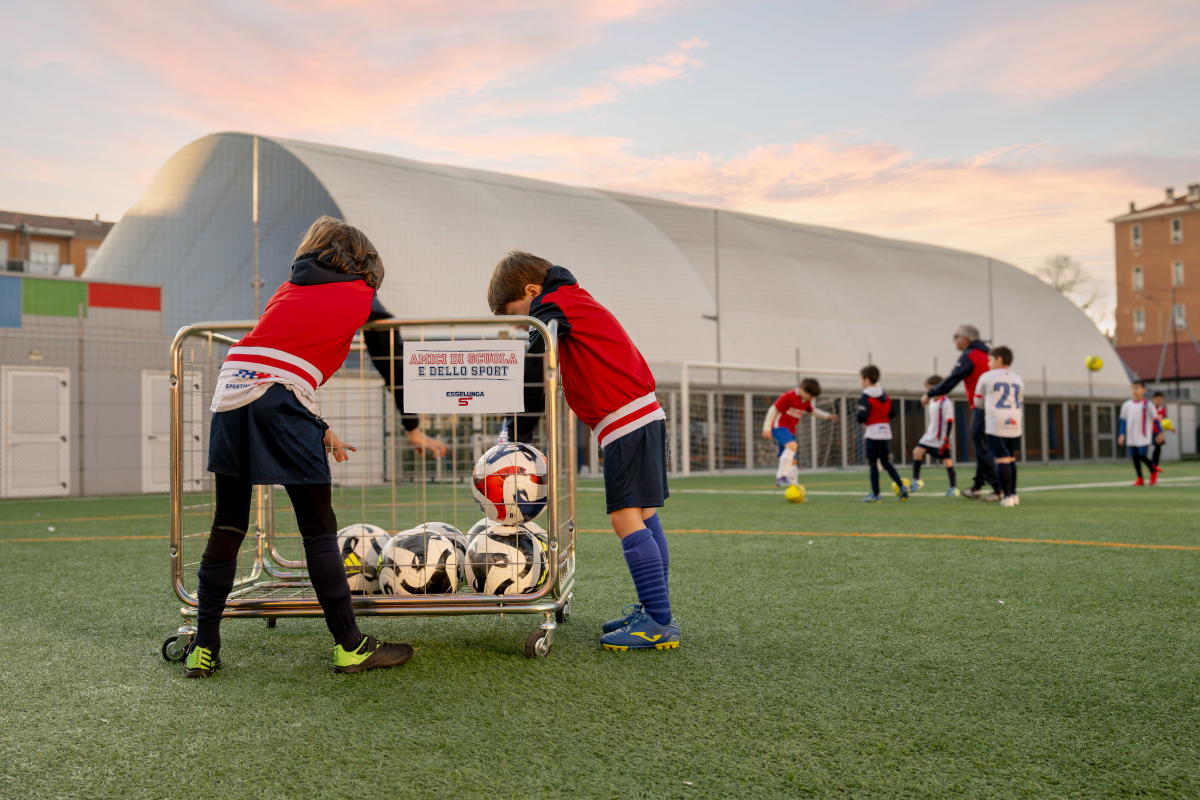 Bambini giocano a calcio con Esselunga Amici di Scuola e dello Sport. Palloni e campo da calcio.