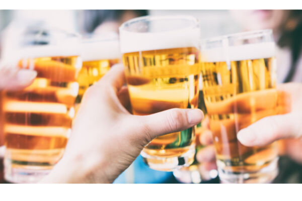 Brindisi con birra. Mani che alzano bicchieri di birra chiara. Festeggiamenti con birra. - AssoBirra