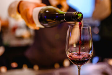 Versando vino rosso in un bicchiere. Degustazione vino Piccini 1882.