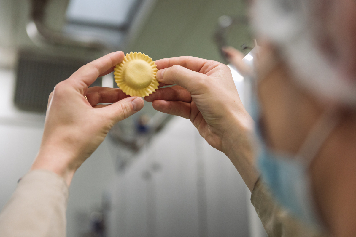 Raviolo artigianale in mano. Pasta fresca ripiena, produzione di qualità-Raviolificio Scoiattolo