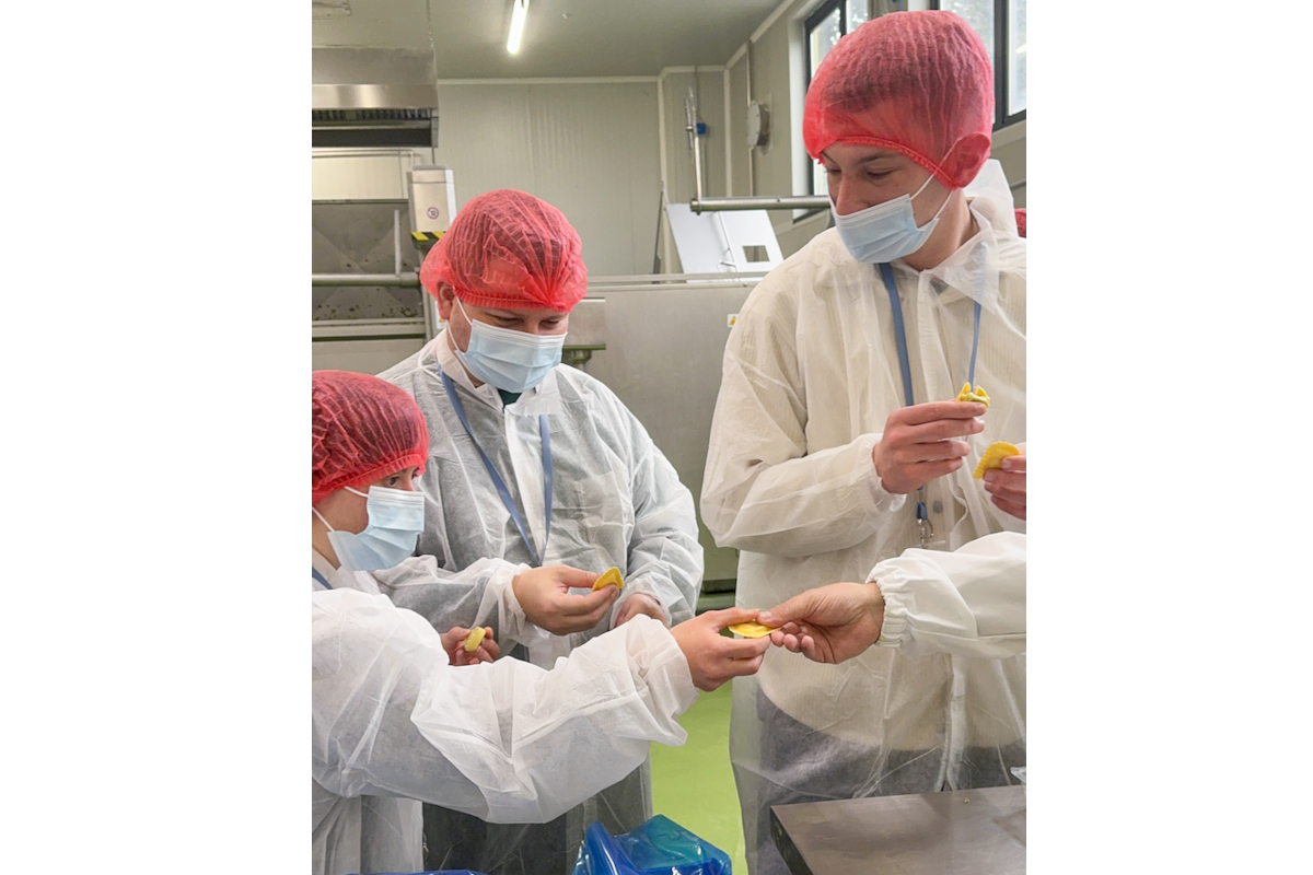 Visita al Ravioificio Scoiattolo: gruppo assaggia ravioli in produzione. Amici, cibo, sicurezza alimentare.