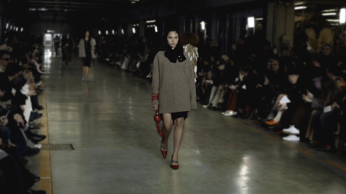 Sfilata Envy™ a Milano: modella con abito e accessori rossi. Collezione moda, piacere ed eleganza.