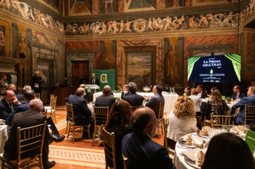 Evento olio evo: La Prima Dell'Olio. Sala affrescata, pubblico seduto, relatore al podio. Nuove forme di comunicazione.