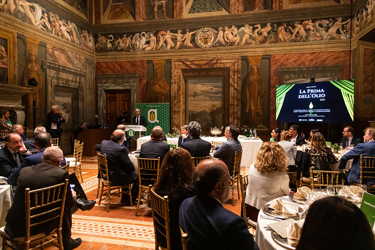 Evento olio evo: La Prima Dell'Olio. Sala affrescata, pubblico seduto, relatore al podio. Nuove forme di comunicazione.