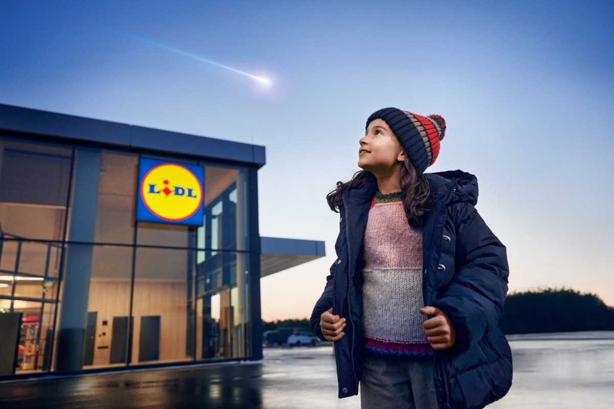 Bambina guarda stella cadente davanti a Lidl. Campagna Natale Lidl, sogni e desideri.