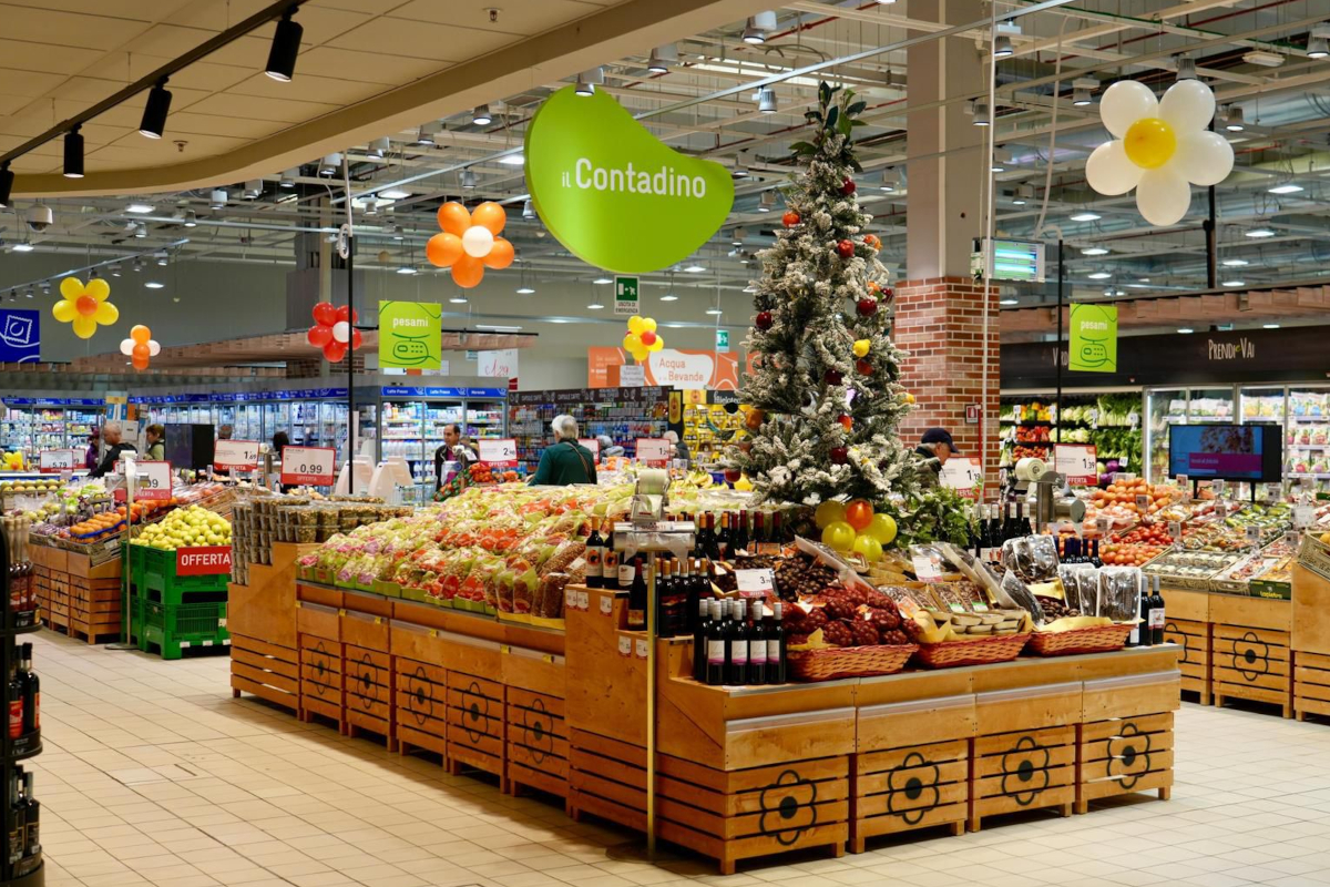 Spazio Conad Gran Sasso: reparto ortofrutta con frutta fresca, albero di Natale decorato e palloncini colorati.