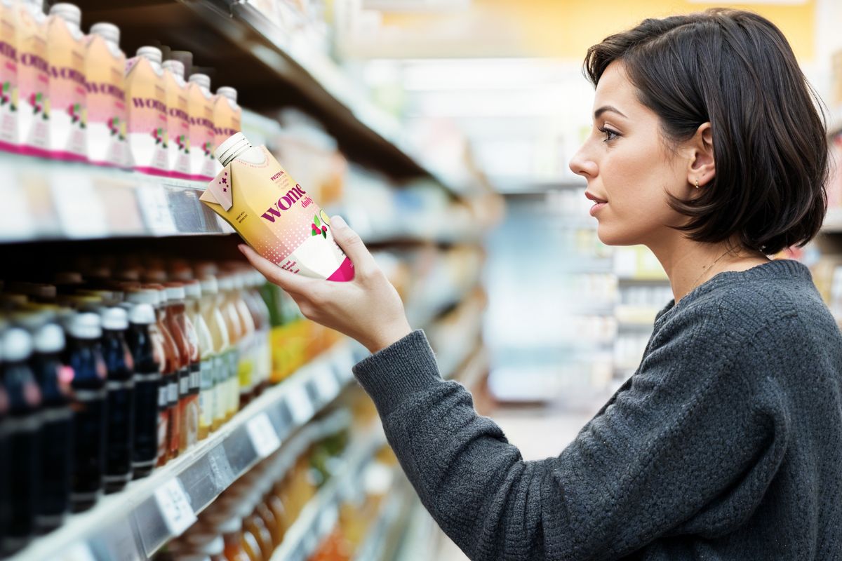 Donna guarda bevanda Wome Daily. Trend nutrizione Tetra Pak: bevande salutari, alimentazione sana, benessere.