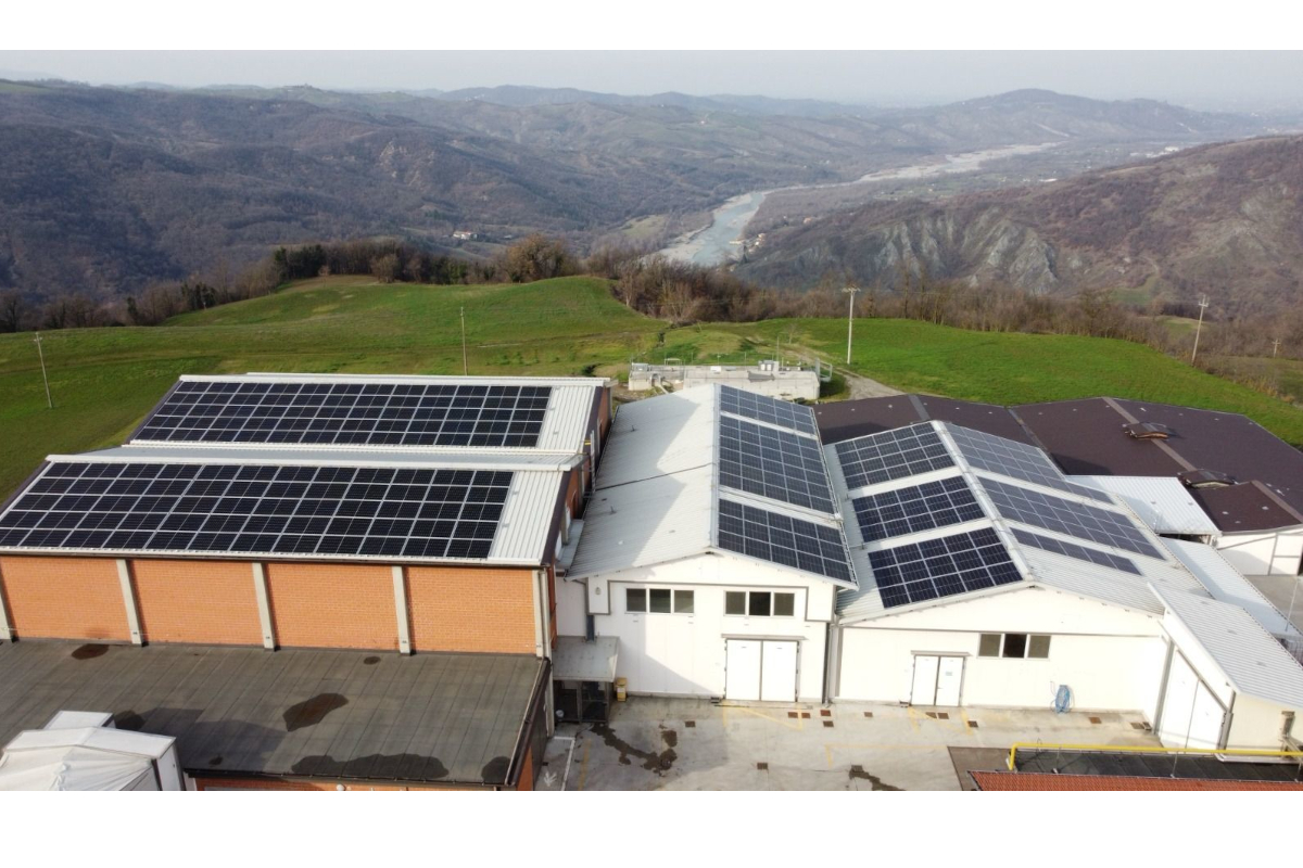 Edifici con pannelli fotovoltaici sui tetti, energia solare rinnovabile. Colline sullo sfondo.