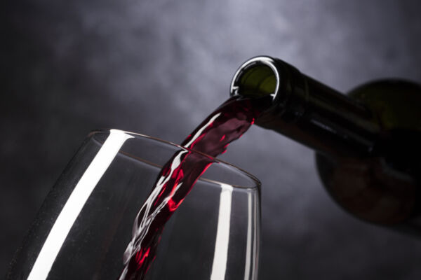 vini dealcolati-Vino dealcolato italiano. Bottiglia che versa vino rosso in un bicchiere.