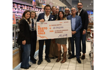 Worldcoo Italia: consegna assegno Famila per beneficenza. Gruppo di persone con cartello donazione.