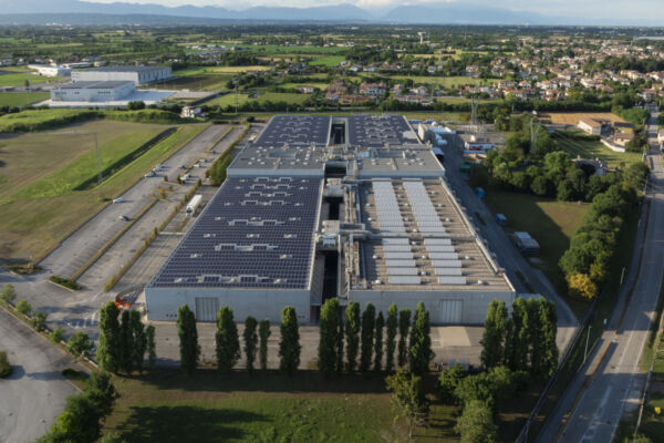 Veduta aerea azienda MC Tech. Pannelli solari sul tetto, parcheggio e area verde.