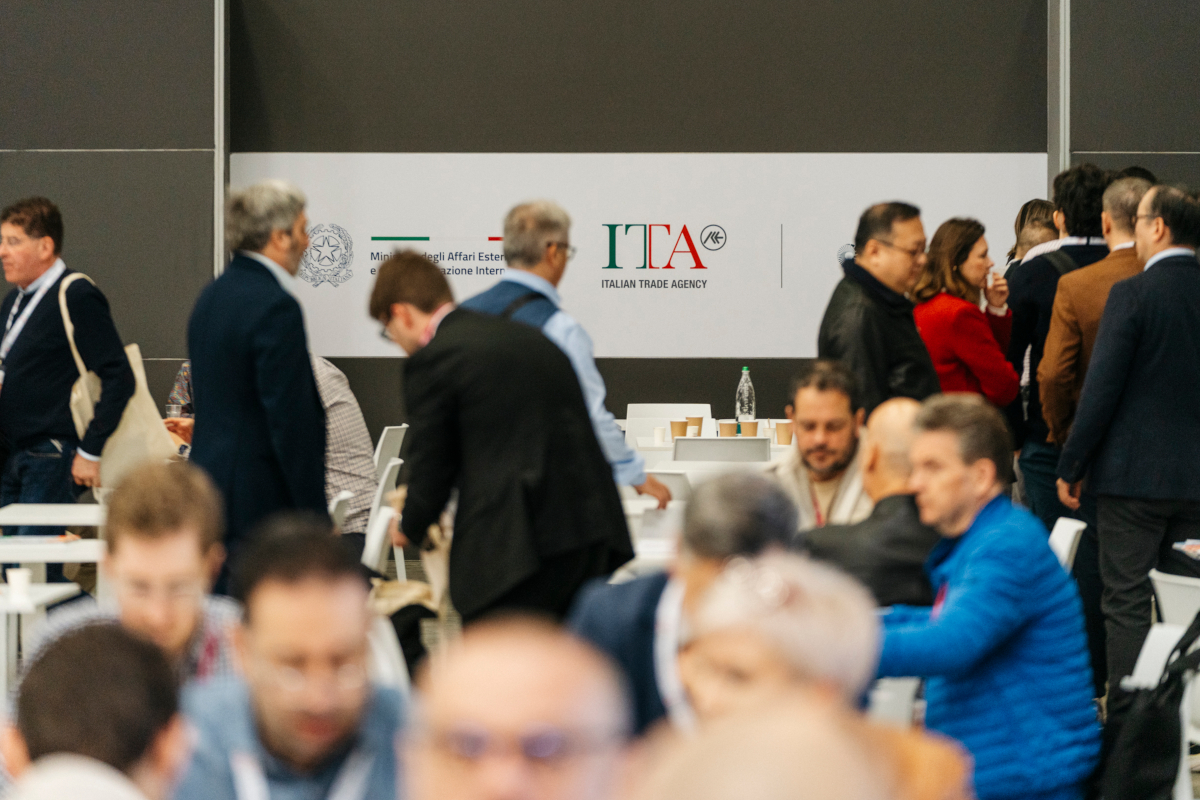 Folla a evento ITA (Italian Trade Agency). Persone, tavoli, logo ITA. Promozione commerciale italiana. - Bio-biologico