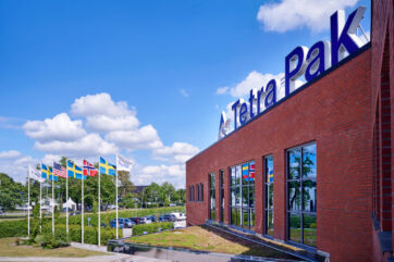 Stabilimento Tetra Pak a Lund, Svezia. In primo piano le bandiere e l'edificio in mattoni rossi con logo.