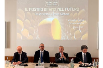 Conferenza Parmigiano Reggiano: dati economici e futuro del brand. Relatori e slide sullo schermo.
