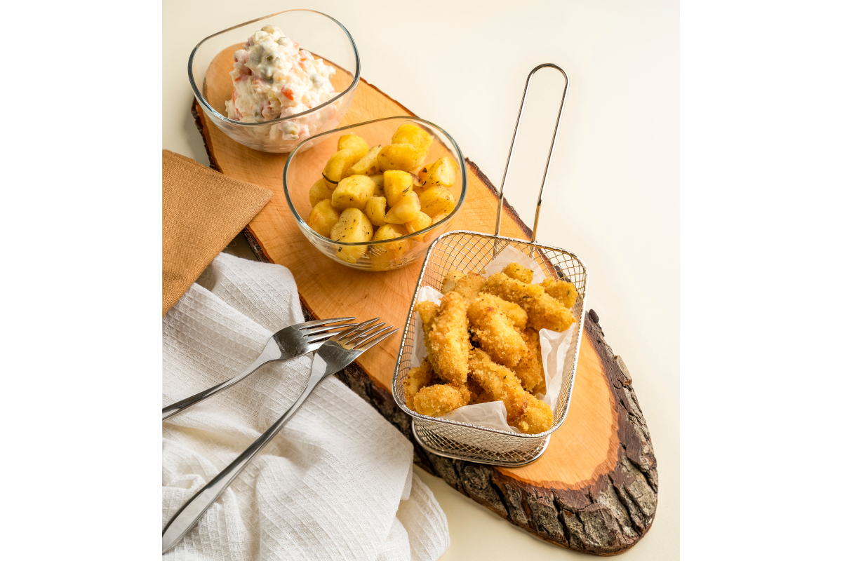 Parmachef-Cibo gustoso su tagliere: bastoncini di pollo fritti, insalata russa e patate. Forchette e tovagliolo.