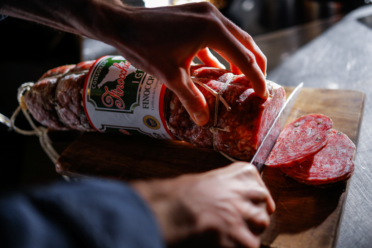 Finocchiona IGP tagliata su tagliere. Salume toscano artigianale.