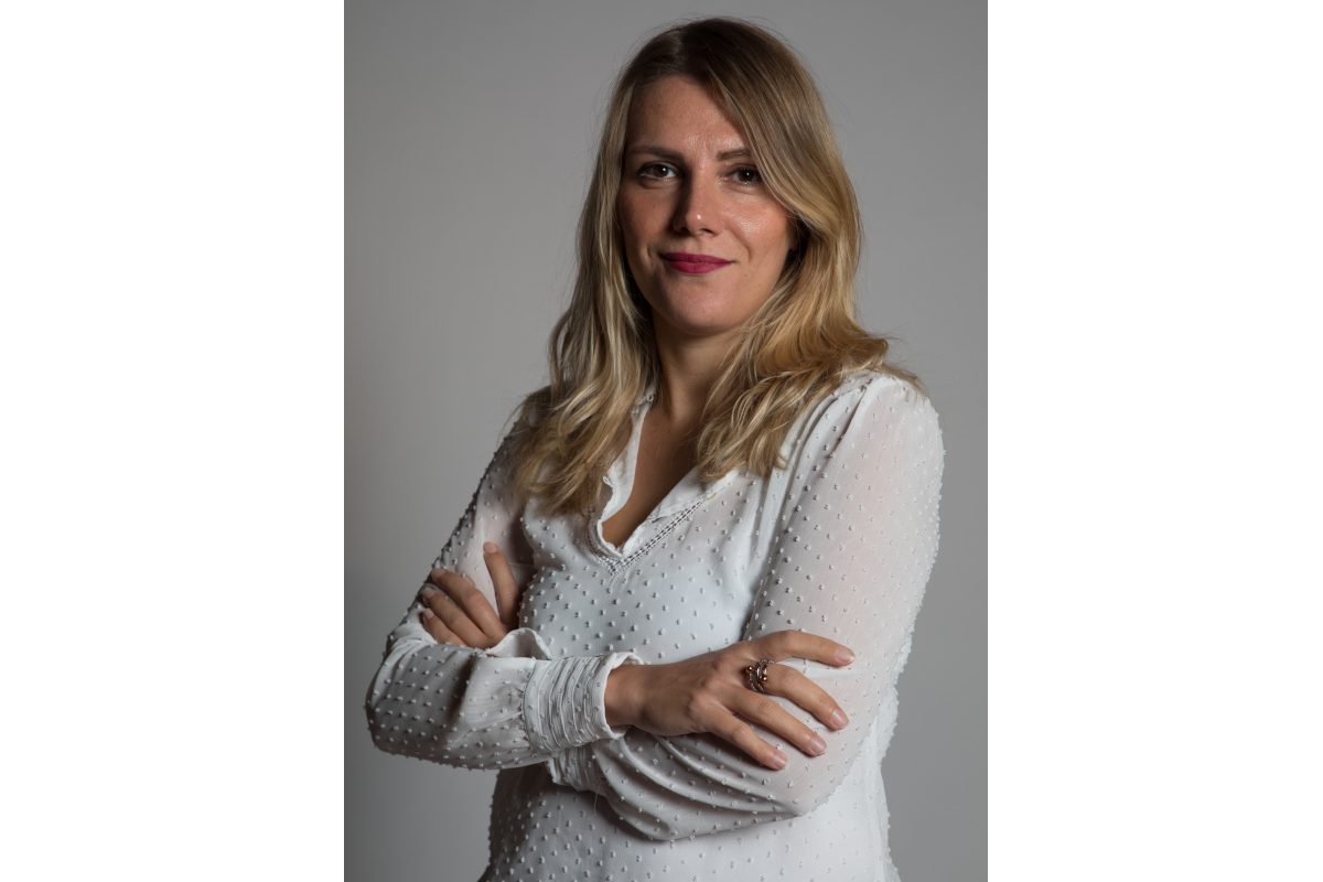 Ritratto di Gasparrini, donna bionda con camicia bianca. Sguardo diretto, braccia conserte. Foto professionale per profilo. - Danone