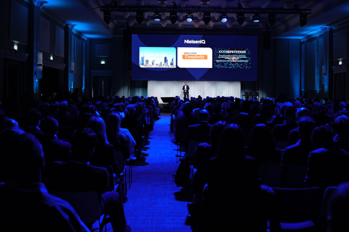 Sala Insight Summit 2026 NIQ: pubblico, palco con relatore e schermo. Evento largo consumo.