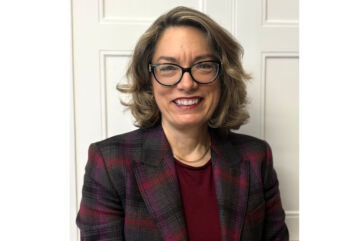 Valerie Diele-Braun, CEO Nexture. Ritratto di donna sorridente con giacca a quadri.