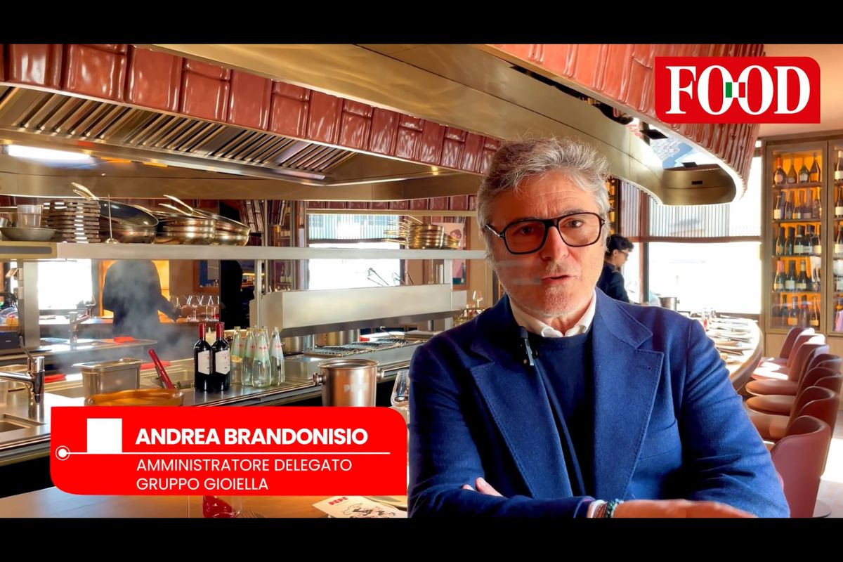 Andrea Brandonisio, AD Gruppo Gioiella, parla di eccellenza casearia a Milano. Cucina professionale sullo sfondo.