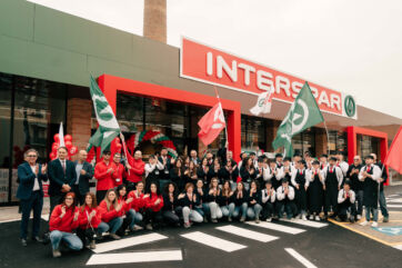 Maiora-Inaugurazione Interspar: gruppo di persone festeggiano davanti al nuovo supermercato. Bandiere e sorrisi.