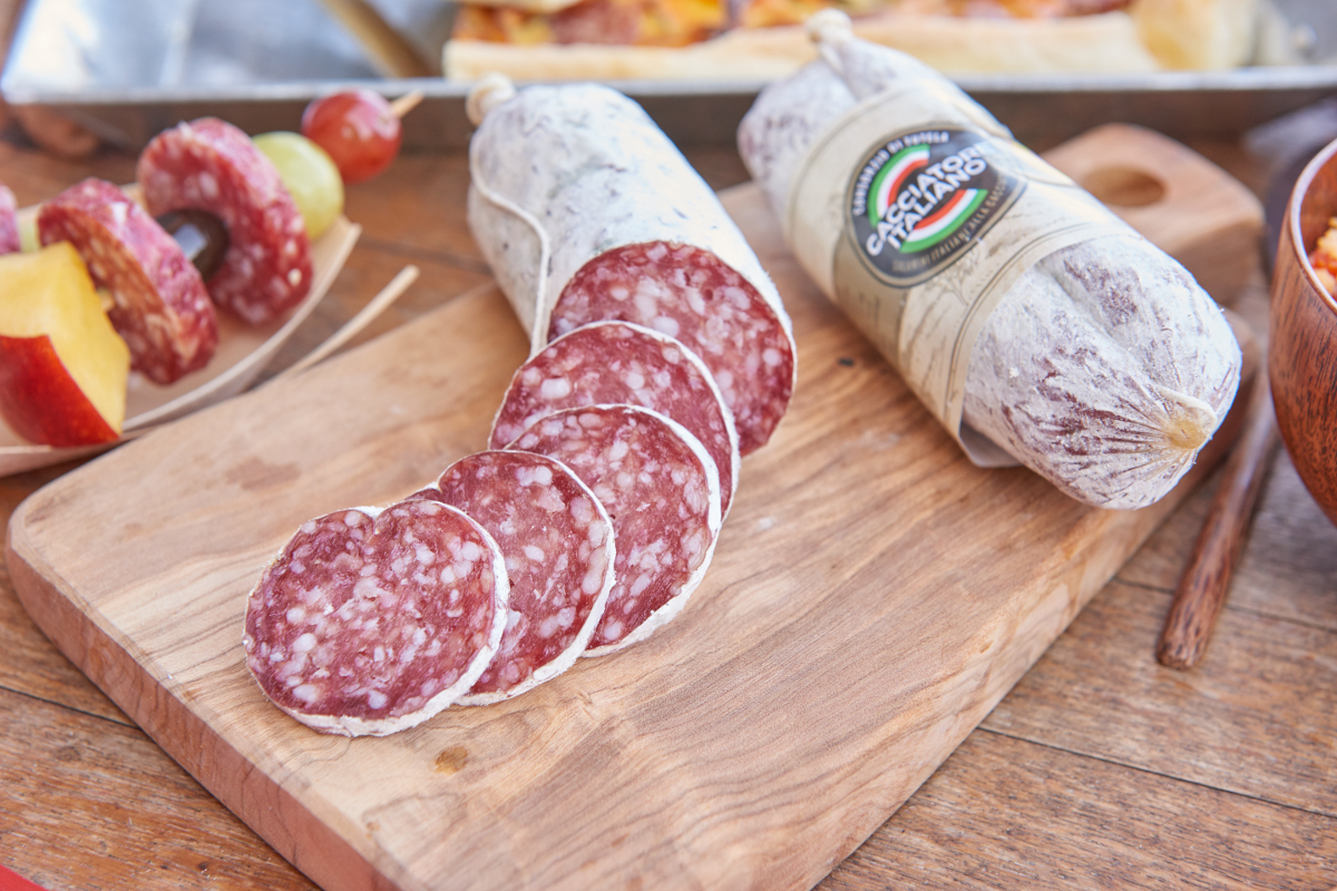 Salame Cacciatore Italiano Dop su tagliere. Salumi tipici italiani, affettati e interi. Gustoso antipasto con salame.