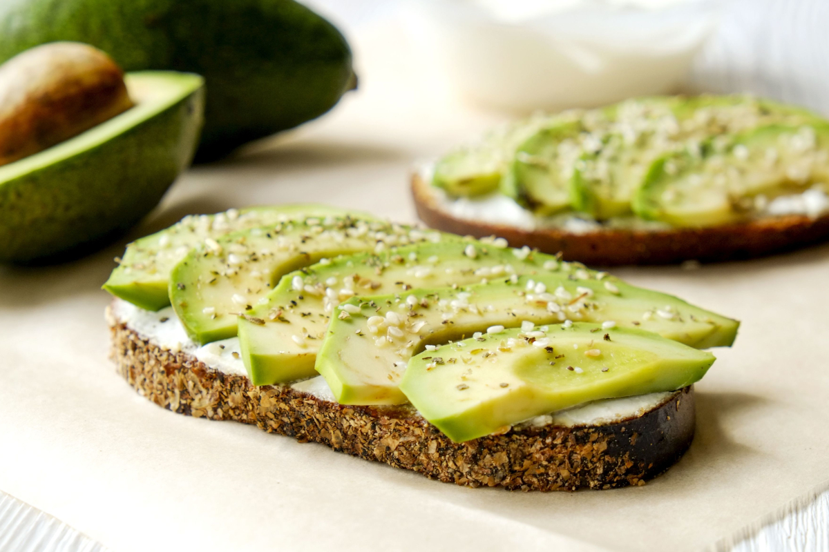 Toast di avocado. Pane tostato con avocado, formaggio spalmabile e semi. Colazione sana e gustosa.