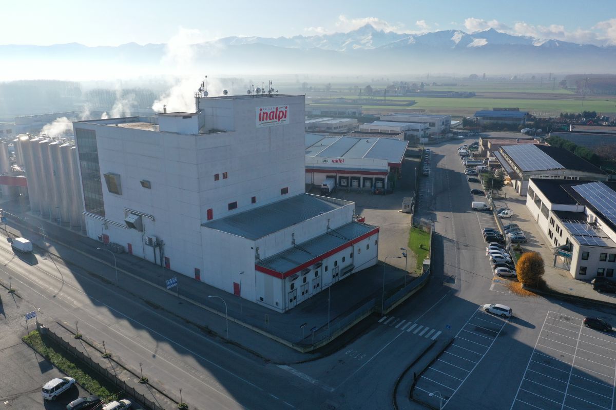 Stabilimento Inalpi: produzione latte hi-tech. Vista aerea della fabbrica con montagne sullo sfondo.