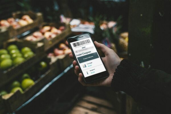 Coupon digitali al supermercato. Mano con smartphone e app per la spesa. Offerte e sconti sullo schermo.