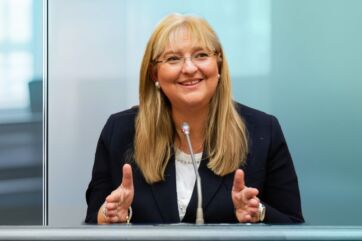 Ritratto di Zucchi, politica italiana, sorridente. Indossa giacca blu e occhiali.