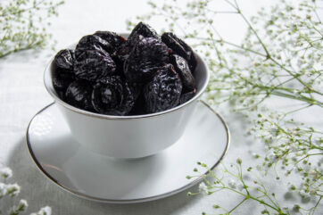 Prugne della California in ciotola bianca. Frutta secca, snack salutare.