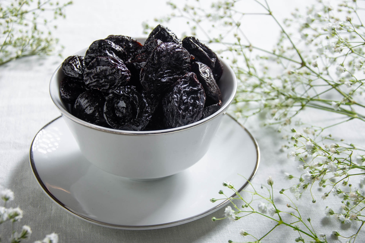 Prugne della California in ciotola bianca. Frutta secca, snack salutare.