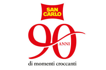 Logo San Carlo 90 anni: celebrazione del marchio italiano di patatine. Grafica rossa e gialla, momenti croccanti.