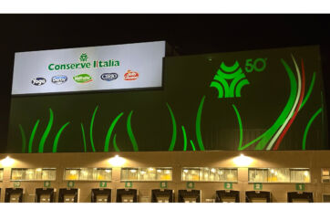 Conserve Italia: stabilimento Pomposa illuminato per il 50° anniversario. Logo Conserve Italia e marchi Yoga, Derby, Cirio, Valfrutta.