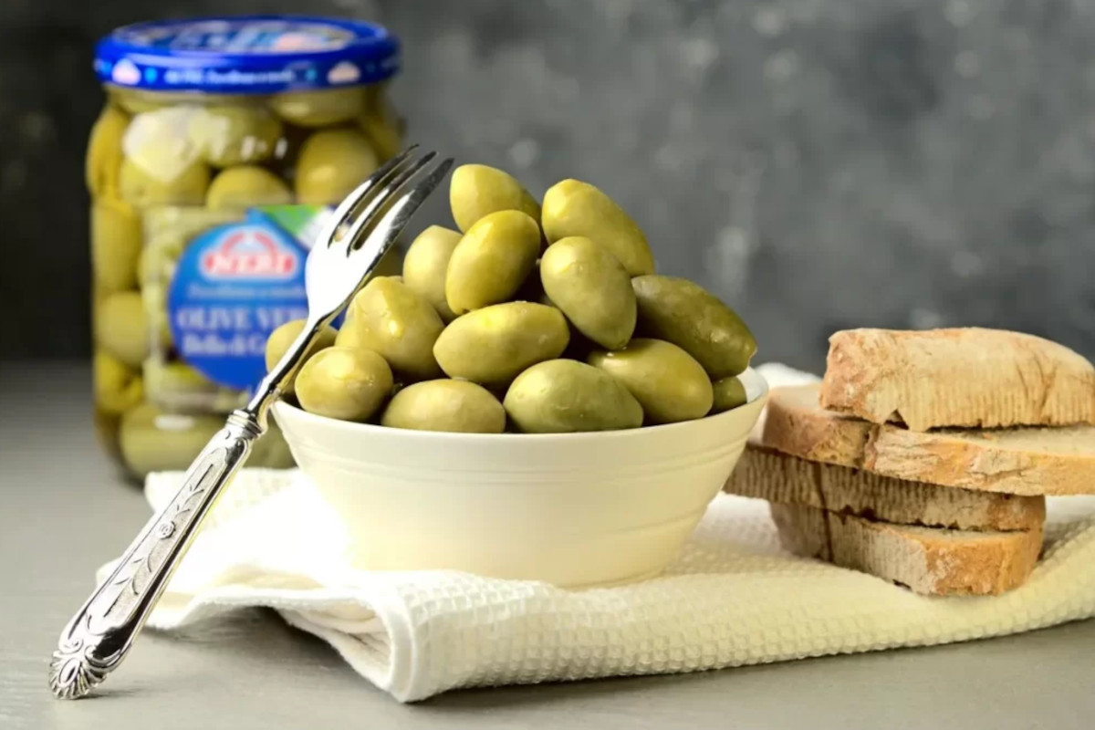 Olive Neri Sottoli in ciotola con pane. Nesti Conserve salva il marchio.