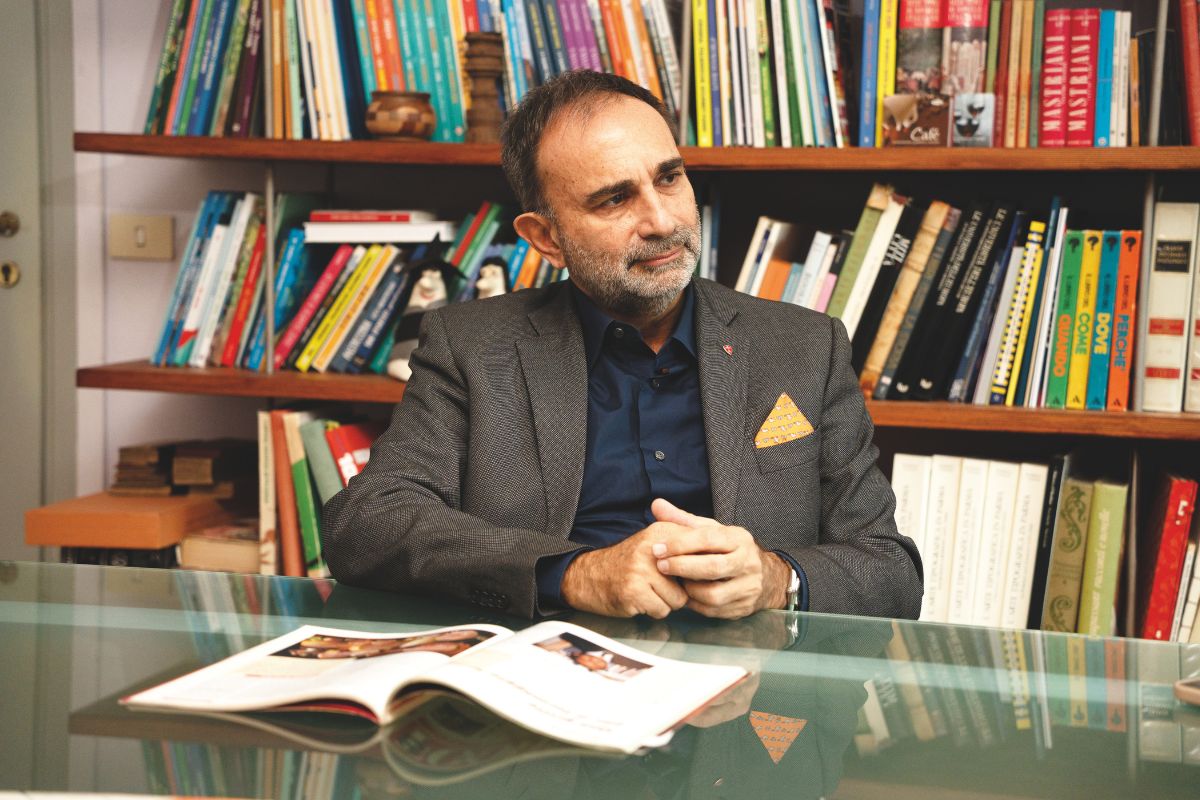 Ritratto di Auricchio, protagonista di Food 35, seduto con libro. Libreria piena sullo sfondo. Corsi e ricorsi.