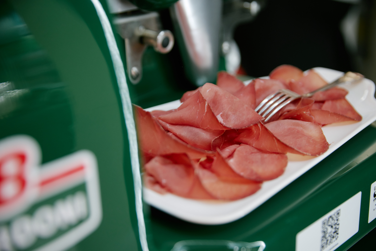 Bresaola Bordoni affettata su piatto bianco con forchetta. Salume tipico italiano.