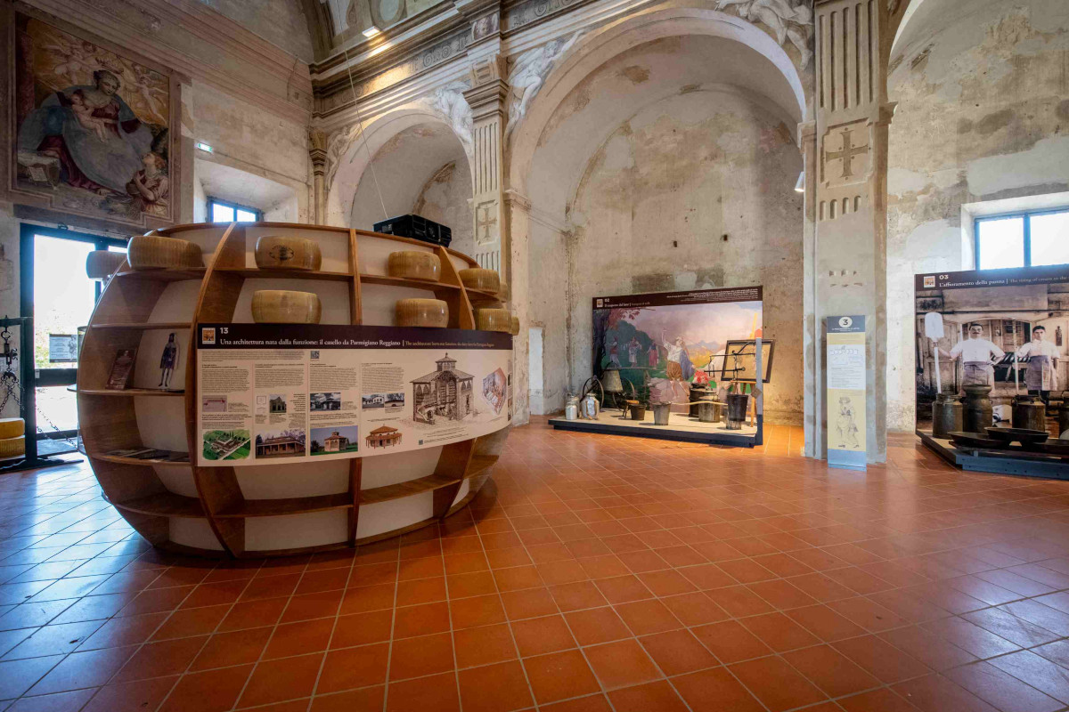 Interno del Museo del Parmigiano Reggiano con espositori a forma di forma di formaggio e pannelli informativi storici.