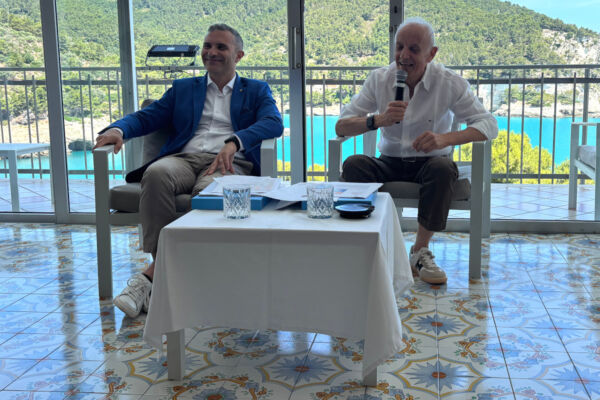 Conferenza Conad Adriatico: due manager in conversazione su una terrazza vista mare per la strategia aziendale 2026.