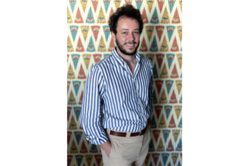 Lorenzo Bagnoli, Vice presidente di Sammontana S.p.A. Società Benefit, sorridente con camicia a righe su sfondo decorato.