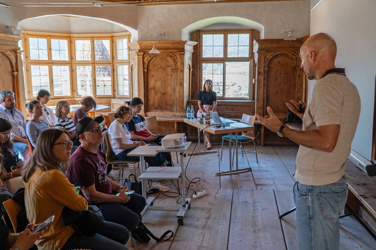 Relatore tiene una presentazione sulle mele della Val Venosta davanti a un pubblico in una sala storica in legno.