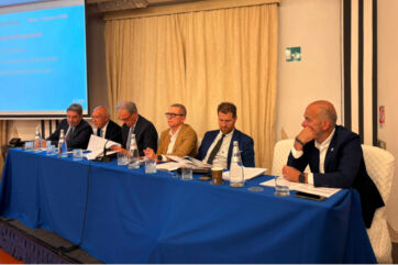 Assemblea dei soci Etruria Retail: relatori al tavolo presidenziale durante la presentazione dei risultati economici 2025.