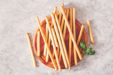 Grissini artigianali su tagliere di legno, eccellenza del bakery salato Made in Italy per l'export internazionale.